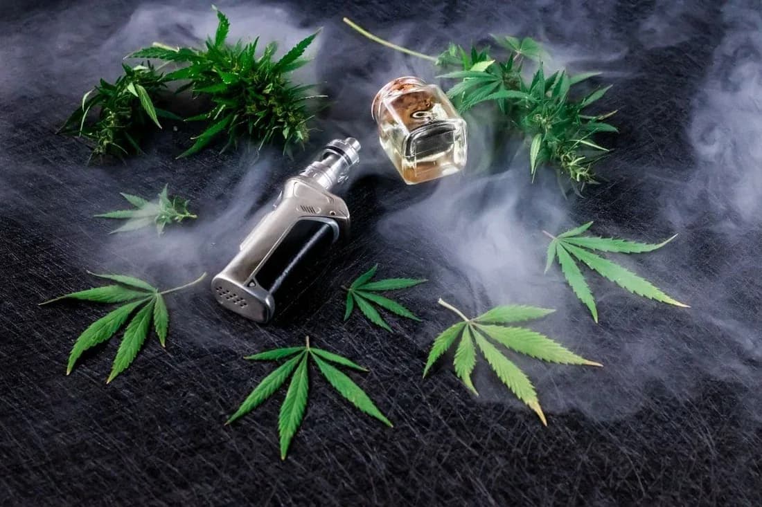 Darwin CBD vape juice bottle beside a refillable vape device and hemp leaves