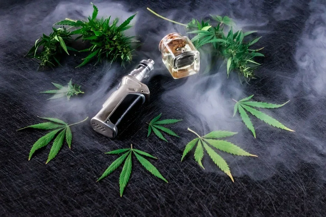 Darwin CBD vape juice bottle beside a refillable vape device and hemp leaves